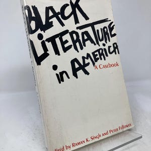 Puede incluir: Un libro titulado "Black Literature in America: A Casebook" con texto negro sobre una portada blanca. El libro est&aacute; apoyado en un soporte de pl&aacute;stico transparente. La portada del libro tambi&eacute;n incluye los nombres de los editores.