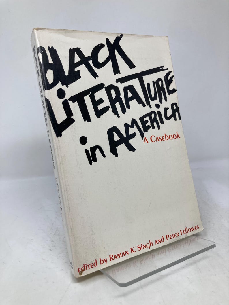 Puede incluir: Un libro titulado "Black Literature in America: A Casebook" con texto negro sobre una portada blanca. El libro est&aacute; apoyado en un soporte de pl&aacute;stico transparente. La portada del libro tambi&eacute;n incluye los nombres de los editores.
