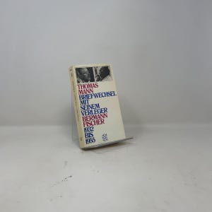 Op de afbeelding: Een paperback boek getiteld Thomas Mann Briefwechsel mit seinem Verleger Bermann Fischer 1932 bis 1955. De gebroken witte kaft bevat twee kleine zwart-wit portretfoto's aan de bovenkant en tekst gedrukt in afwisselend rode en blauwe inkt.