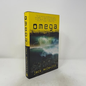May include: A hardcover book titled Omega by Jack McDevitt with a yellow spine and cover top. The cover features a dark landscape with a lightning storm over a city. The text reads: In his ability to absolutely rivet the reader, it seems to me that McDevitt is the logical heir to Isaac Asimov and Arthur C. Clarke. -Stephen King.