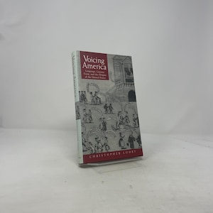 以下が含まれることがあります： 「Voicing America」というタイトルのハードカバー本。赤と白の表紙で、人々や建物のイラストが描かれています。著者の名前、Christopher Loobyは下部に印刷されています。