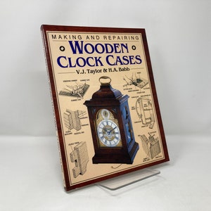 May include: Book cover with the title "Making and Repairing Wooden Clock Cases" by V.J. Taylor & H.A. Babb. The cover features a detailed illustration of a wooden clock case with various clockmaking techniques.