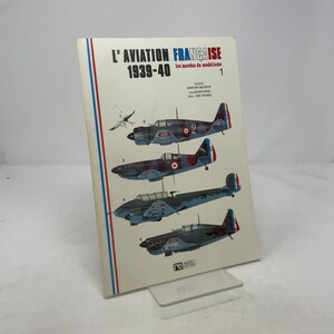 May include: A book titled "L'AVIATION FRANÇAISE 1939-40" with illustrations of French aircraft. The cover features a white background with red and blue vertical stripes on the left side. The book displays several aircraft models.