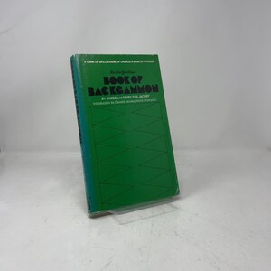 May include: A green book titled "Book of Backgammon" by James and Mary Zita Jacoby. The book has a green cover with a backgammon board design and the text "The New York Times". The book is a guide to the game of backgammon.