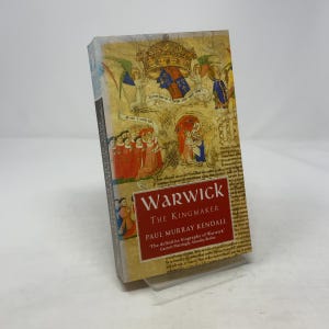 Pode incluir: Um livro de capa dura intitulado "Warwick The Kingmaker" de Paul Murray Kendall. A capa apresenta uma ilustração histórica com uma coroa e figuras em vermelho e azul. O livro está em um suporte de plástico transparente.