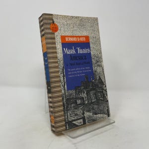 Peut inclure: Un livre de poche intitulé Mark Twain's America & Mark Twain at Work par Bernard DeVoto. La couverture présente une illustration en noir et blanc d'une maison, un bloc rectangulaire bleu avec du texte blanc et un dos beige à motifs.