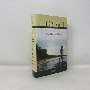 Può includere: Un libro con copertina rigida intitolato "Huck's Raft: A History of American Childhood" di Steven Mintz. La copertina presenta un ragazzo su una zattera su un fiume. Il dorso recita "Huck's Raft". Il libro ha una copertina giallo chiaro e un dorso verde scuro.