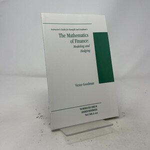 May include: A white softcover book titled Instructor's Guide for Stampfli and Goodman's The Mathematics of Finance: Modeling and Hedging by Victor Goodman. The cover features a dark green vertical rectangle on the right and black text.