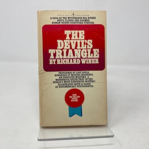 Puede incluir: Una portada de libro de bolsillo con un título rojo y blanco "The Devil's Triangle" de Richard Winer. La portada presenta un fondo blanco con texto rojo y un sello rojo y blanco con el texto "Over One Million Copies In Print".