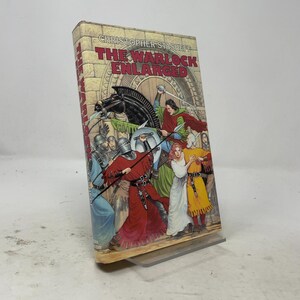 May include: A hardcover book titled The Warlock Enlarged by Christopher Stasheff. The cover features a colorful fantasy illustration of knights in armor, a person in a red robe, and a person in a yellow tunic standing before a stone archway.