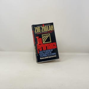 Puede incluir: Un libro negro con un título rojo y dorado "Top Performance" de Zig Ziglar. La portada del libro presenta el texto "America's #1 Motivator" y "Bestselling Author of 26 Books Secrets of Closing the Sale". La portada del libro también incluye el texto "How to Develop Excellence in Yourself & Others Maximize potential-beyond your best!"