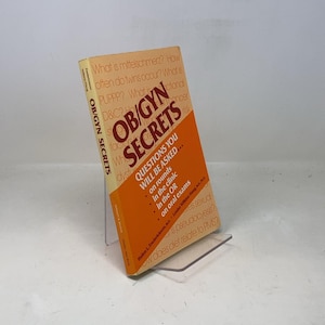 Puede incluir: Un libro amarillo y naranja titulado "OB/GYN Secrets: Questions You Will Be Asked... on rounds, in the clinic, in the OR, on oral exams".