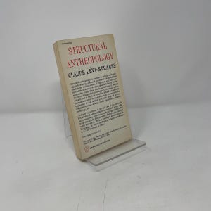 Può includere: Un libro tascabile intitolato Structural Anthropology di Claude Lévi-Strauss con una copertina color crema e testo rosso. La copertina presenta il titolo, il nome dell'autore e un paragrafo descrittivo sui contenuti e i temi del libro.