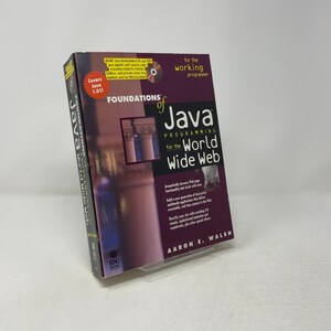 Op de afbeelding: Een paperback boek getiteld Foundations of Java Programming for the World Wide Web door Aaron E. Walsh. De kaft is donkerpaars met witte en gele tekst, voorzien van een kleine afbeelding van zuilen en een CD-ROM-afbeelding.