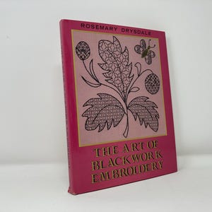 May include: A pink book titled "The Art of Blackwork Embroidery" by Rosemary Drysdale. The cover features a black and white illustration of a stylized flower with a butterfly.