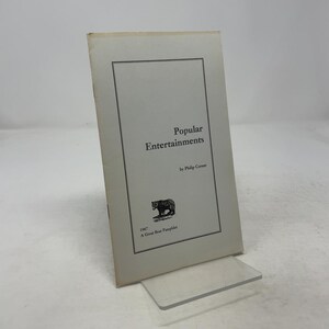 以下が含まれることがあります： フィリップ・コーナー著「Popular Entertainments」と題されたヴィンテージパンフレット。表紙には黒い熊のイラストと「1967 A Great Bear Pamphlet」の文字が描かれています。パンフレットは透明なアクリルスタンドに展示されています。