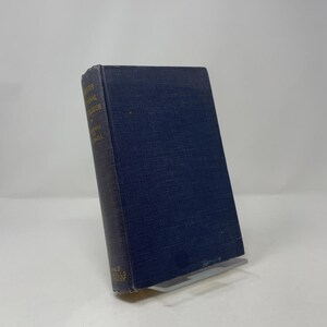 May include: A hardcover book with a dark blue cover and gold lettering. The book is titled "Modern International Equation" by Norman and Cornell. The book is propped up on a clear plastic stand.