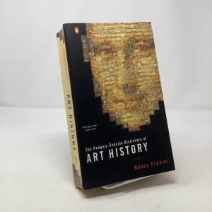 Peut inclure: Un livre relié noir avec une couverture en mosaïque colorée représentant un visage. Le titre est "The Penguin Concise Dictionary of Art History" par Nancy Frazier.