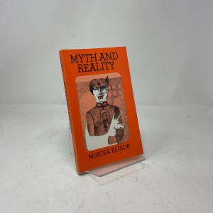 May include: An orange book titled "Myth and Reality" by Mircea Eliade. The cover features an illustration of a person with a question mark and a unicorn. The book is displayed on a clear stand.