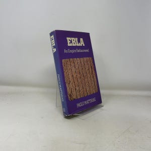 Puede incluir: Un libro de tapa dura titulado "EBLA An Empire Rediscovered" de Paolo Matthiae. El libro tiene una cubierta morada con texto blanco y naranja. La cubierta presenta un patrón marrón texturizado.