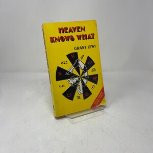 以下が含まれることがあります： グラント・レウィ著の「Heaven Knows What」というタイトルのヴィンテージ本。本は、赤い文字と、十二宮のシンボルに囲まれた逆立ちをしている人の白黒イラストが描かれた明るい黄色の表紙をしています。本は透明なスタンドに表示されています。