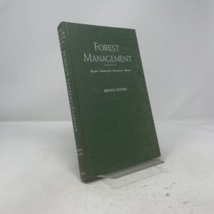 May include: A hardcover book titled "Forest Management" in a dark green cover. The book is propped up on a clear stand. The title and author's names are in white lettering. The words "Second Edition" are also visible.