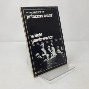 May include: A black and white photo of a playbill for "Princess Ivona" by Witold Gombrowicz. The playbill features a group of actors in costume, including a king, a queen, and a princess.