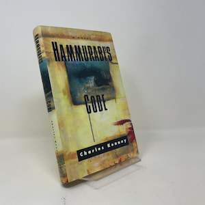 Puede incluir: Un libro de tapa dura titulado Hammurabi's Code de Charles Kenney. La portada presenta un fondo abstracto amarillo y beige con un cuadrado azul oscuro en el centro. El título está impreso en letras negras negritas y el autor abajo.
