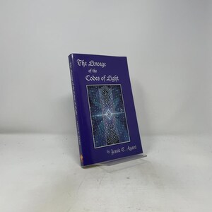 May include: A purple book titled The Lineage of the Codes of Light by Jessie E. Ayani. The cover features white text and a central rectangular illustration depicting a glowing, geometric, star-like pattern against a dark blue, starry background.