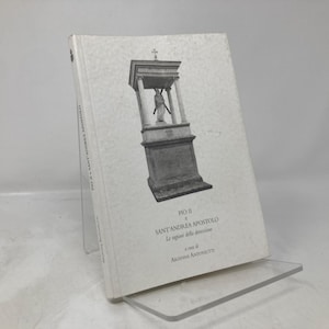 May include: A white book with the title "Pio II e Sant'Andrea Apostolo" and the text "Le ragioni della destinazione a cura di Adriano Antinucci". The cover features a black and white image of a religious structure.