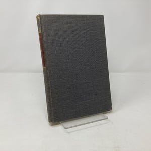 May include: A dark gray hardcover book with a gold spine and a red label on the spine.