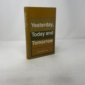 May include: A hardcover book titled "Yesterday, Today and Tomorrow" with a mustard yellow cover. The title is in white and green text. The book's spine reads "Yesterday". The author's name is Simon John DeVries.