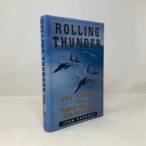 May include: A hardcover book titled "Rolling Thunder" with a blue cover featuring fighter jets. The book's subtitle reads "Jet Combat from World War II to the Gulf War" by Ivan Rendall.
