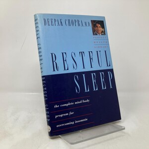 May include: A blue and black book titled "Restful Sleep: The Complete Mind/Body Program for Overcoming Insomnia" by Deepak Chopra, M.D.