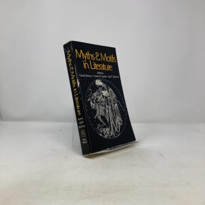 May include: A hardcover book titled "Myths & Motifs in Literature" with a black cover and gold lettering. The book features an illustration of figures in a circle. The book is propped up on a clear stand.