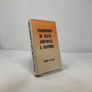 May include: A vintage book titled "Theosophies of Plato, Aristotle & Plotinus" with an orange and cream cover. The book is propped up on a clear stand. The title and author's name are printed in black.