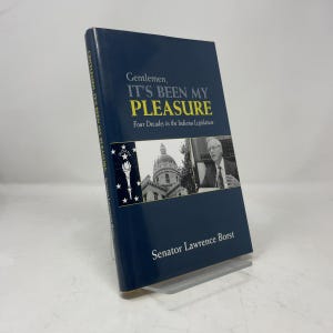 Może przedstawiać: Książka w twardej oprawie zatytułowana Gentlemen, It's Been My Pleasure: Four Decades in the Indiana Legislature autorstwa senatora Lawrence'a Borsta. Ciemnoniebieska okładka zawiera czarno-białe zdjęcie kopuły budynku i mężczyzny w garniturze.