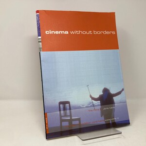 May include: A book titled "cinema without borders" with a red cover and a photo of a person standing in a field with a chair and a pole. The text "The Films" and "Joris Ivens" are visible on the cover.