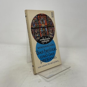 May include: A paperback book titled Das Heilige und das Profane by Mircea Eliade. The off-white cover features a circular stained glass illustration at the top and a blue circle below containing the title text in black, stylized gothic lettering.