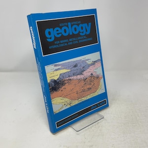 以下が含まれることがあります： Jos Lurie著の青いハードカバーの教科書「South African Geology for Mining, Metallurgical, Hydrological and Civil Engineering」。表紙には地質図のイラストと、白色で「Eighth Revised Edition」という文字が記載されています。