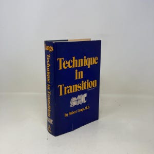 以下が含まれることがあります： ロバート・ラングス著「Technique in Transition」というタイトルのハードカバー本。本は濃い青色の表紙に黄色の文字が書かれています。タイトルが大きく表示されており、背表紙にもタイトルが記載されています。本は直立しています。