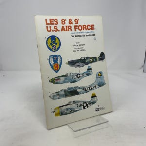 May include: A vintage book titled "LES 8° & 9° U.S. AIR FORCE" with illustrations of WWII-era airplanes. The cover features a blue and white emblem with the number 9, and the text "les mordus du modélisme".