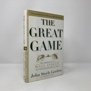 May include: A white book with a green title, "The Great Game: The Emergence of Wall Street as a World Power 1633-2000" by John Steele Gordon. The book is part of the CNBC series "The Great Game".