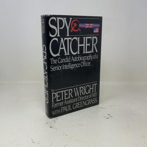 May include: A hardcover book titled Spycatcher: The Candid Autobiography of a Senior Intelligence Officer by Peter Wright with Paul Greengrass. The black dust jacket features white text, a red hammer and sickle, and a British flag graphic.