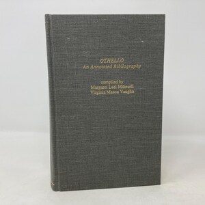 Puede incluir: Un libro de tapa dura de color gris oscuro con el título "OTHELLO An Annotated Bibliography" y el texto "compiled by Margaret Lael Miksell Virginia Mason Vaughn" en la portada.