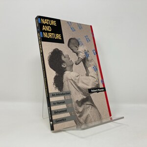 May include: A book titled "Nature and Nurture: An Introduction to Human Behavioral Genetics" by Robert Plomin. The cover features a black and white photo of a woman holding a baby.