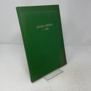 Könnte beinhalten: Ein grünes Hardcover-Buch mit dem Titel Studia Troica 1 1991 und goldener Schrift auf dem Vorderdeckel. Das Buch steht aufrecht auf einem durchsichtigen Kunststoffständer. Der Buchrücken zeigt ebenfalls den Titel und das Jahr in goldener Schrift.