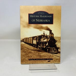 May include: A book titled "Historic Railroads of Nebraska" from the "Images of Rail" series. The cover features a sepia-toned image of a steam train with a long line of boxcars, billowing smoke, and the names Michael M. Bartels & James J. Reisdorff.