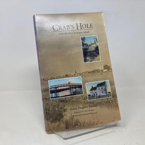 May include: A book titled "Crab's Hole: A Family Story of Tangier Island" by Anne Hughes Lander. The cover features a vintage photograph of a bridge and a house.