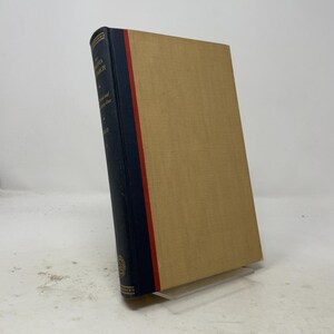 May include: A hardcover book with a tan cover and a dark blue spine featuring a thin red vertical stripe. The spine displays gold text that reads The Virginia Monarch, A Historical and Literary Atlas, and Bruce, with small gold decorative accents.